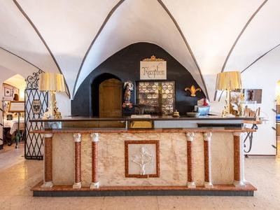 Ein historischer Tresen aus Stein mit dekorativen Säulen und zwei Lampen in einem Raum mit Gewölbedecke.