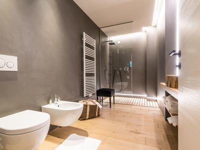 Modernes Badezimmer mit WC, Bidet, begehbarer Dusche und weißem Handtuchheizkörper.