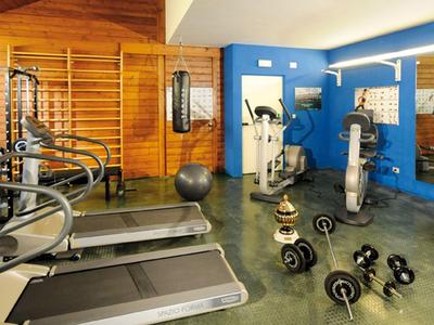 Gym room with various exercise equipment including treadmills, bikes, and dumbbells.