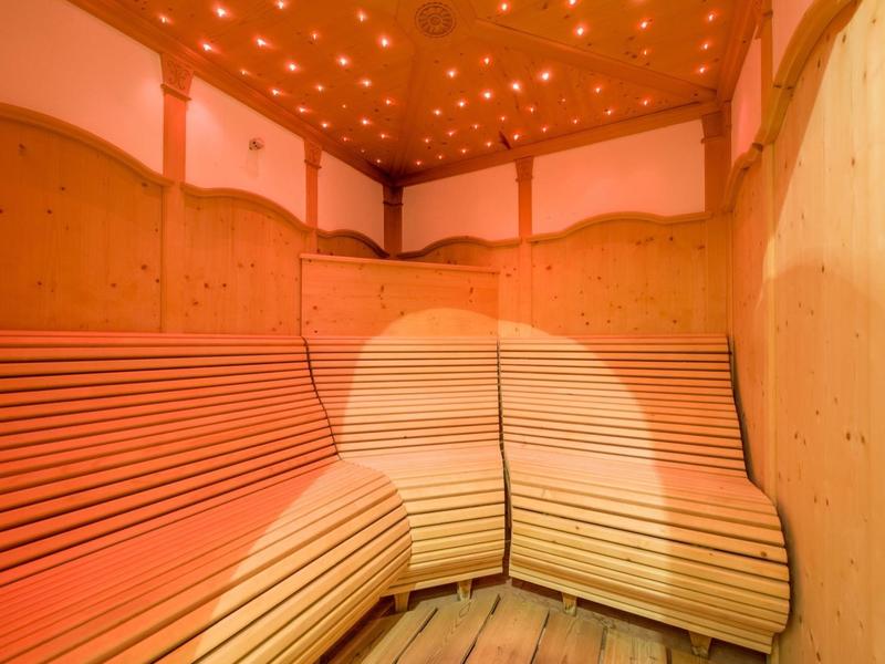 Sauna mit holzverkleideten Wänden und geschwungenen Sitzbänken, warme orange Beleuchtung.