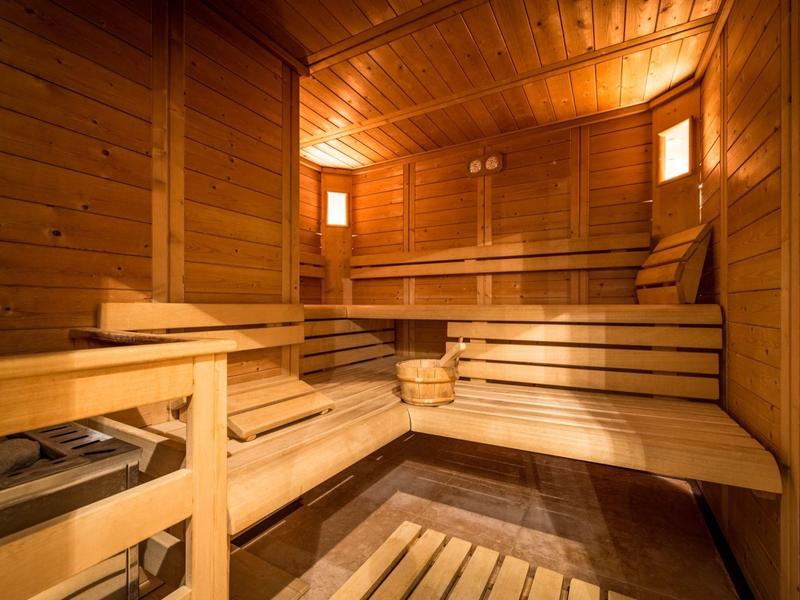 Gemütliche Sauna mit mehrstufigen Holzbänken, Holzverkleidung und warmem Licht.