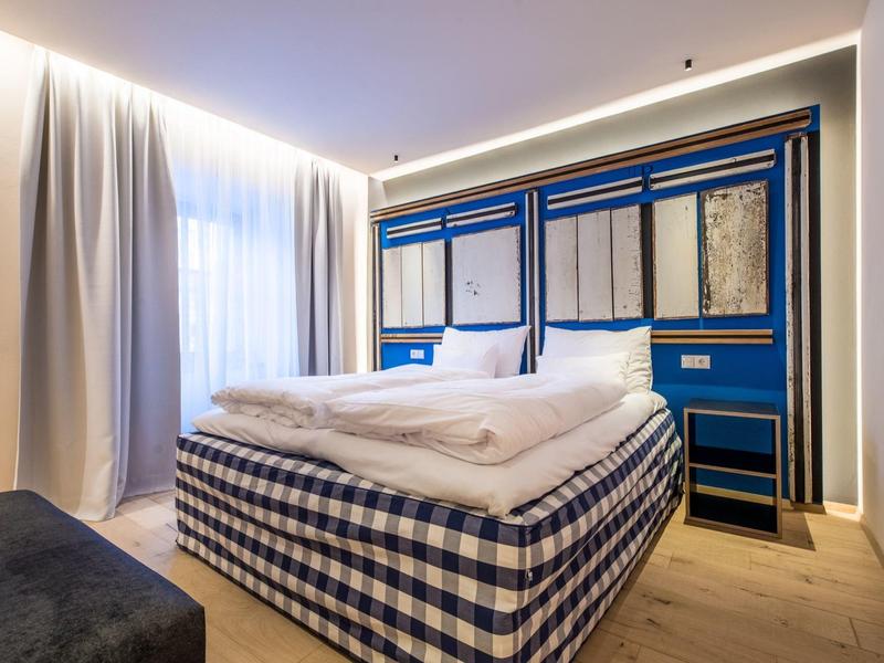 Modernes Schlafzimmer mit Doppelbett, kariertem Bettgestell, blauer Wandgestaltung und großen Vorhängen.