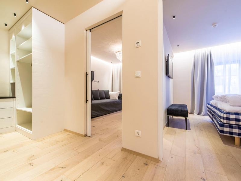 Moderner heller Flur mit Holzfußboden, offenem Kleiderschrank und Blick ins Schlafzimmer.