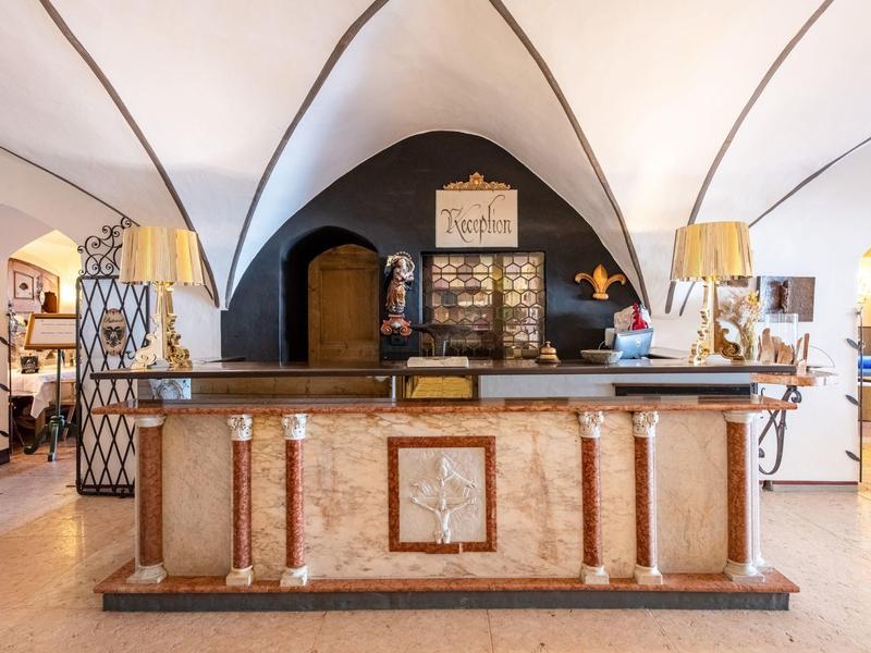 Ein historischer Tresen aus Stein mit dekorativen Säulen und zwei Lampen in einem Raum mit Gewölbedecke.