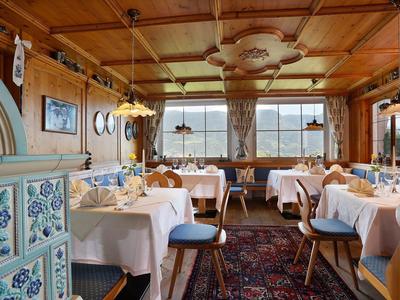 Gemütliches Restaurant mit Holzdecke, weißen Tischdecken, blau gepolsterten Stühlen und großen Fenstern.