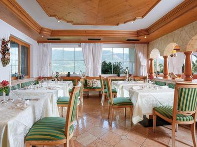 Helles Restaurant mit Holzbalkendecke, grün gestreiften Stühlen und weiß gedeckten Tischen.