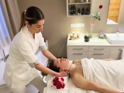 Eine Frau erhält eine Gesichtsmassage in einer hellen, modernen Spa-Behandlungsraum.