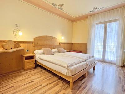 Helles Schlafzimmer mit Holzfußboden, großem Bett, eingebautem Holzschrank und hellem Vorhang.