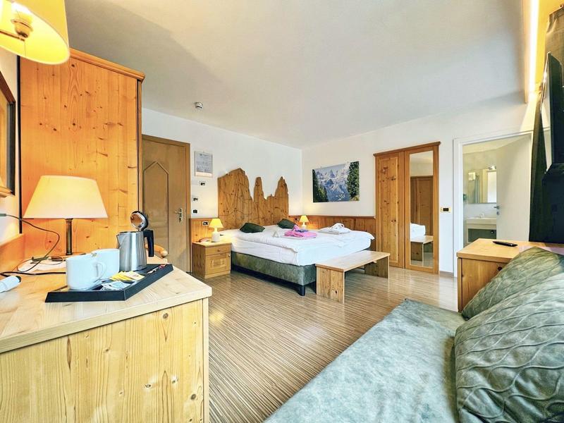 Helles Schlafzimmer mit Holzmöbeln, Doppelbett, Sofa und warmem Licht, modernes Design und sauber.