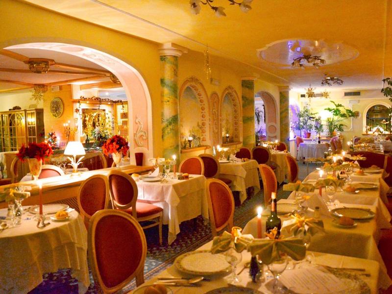 Elegantes Restaurant mit warmem Licht, roten Stühlen, weiß gedeckten Tischen und Pflanzen.