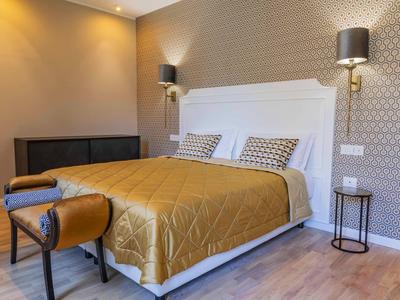 Chambre d'hôtel moderne avec un lit double, une table de chevet et un banc au pied du lit.