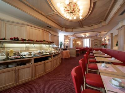 Großer Speisesaal mit rot gepolsterten Stühlen, langen Tischen und Buffetbereich mit Holzverkleidung.