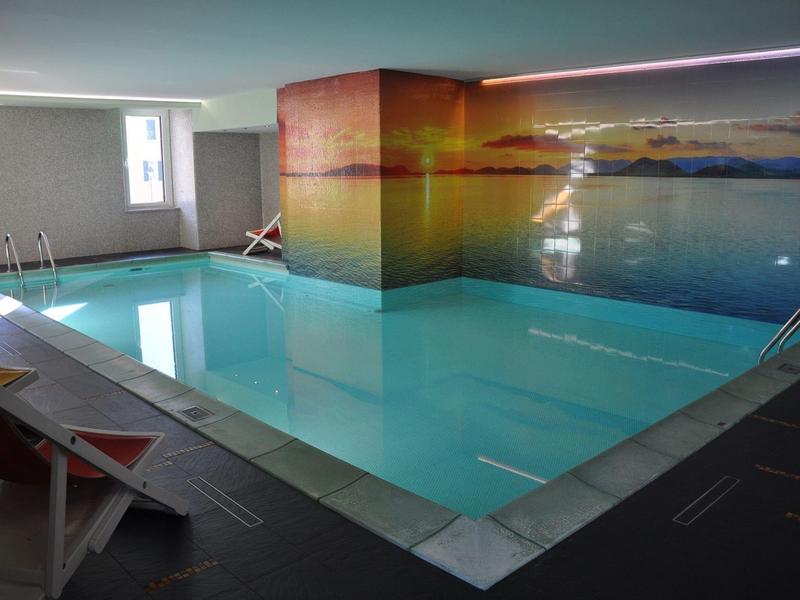 Piscine intérieure avec grande fresque paysagère et espaces de repos latéraux