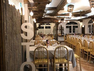 Rustieke restaurantdecoratie met grote letters op hout en lange gedekte tafels.