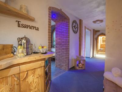 Hell beleuchteter Flur mit blauem Teppich, Holzmöbeln, Tischecke und gemauerter Bogenwand.