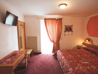 Gezellige hotelkamer met rood tapijt, gordijnen en bedsprei.