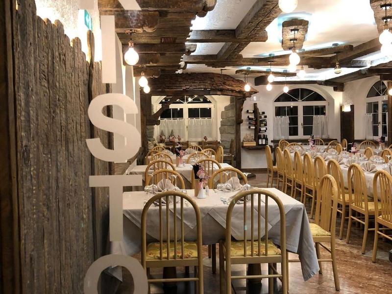 Rustieke restaurantdecoratie met grote letters op hout en lange gedekte tafels.