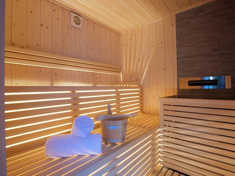 Lichte, moderne sauna met houten bekleding en handdoeken op de bank.
