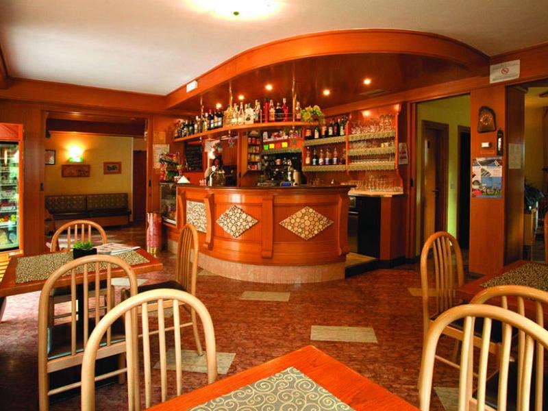 Gezellige bar met houten toonbank, planken vol flessen en meerdere stoelen in warm licht.