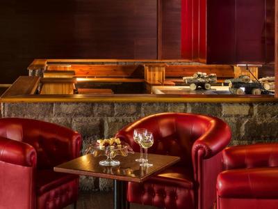 Gemütliche Sitzecke mit roten Ledersesseln und einem Holztablett in einem warm beleuchteten Innenraum.