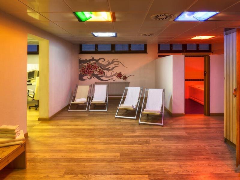 Ruhebereich mit Liegestühlen und Sauna in einem Hotel-Spa mit warmem Licht.