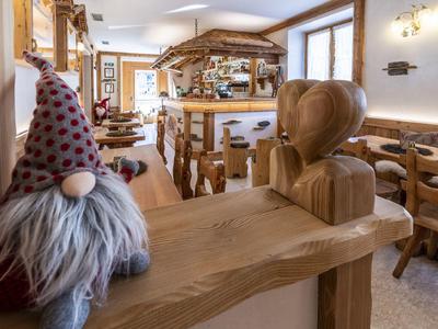 Příjemná hotelová restaurace s rustikálním dřevěným nábytkem a dekorativním skřítkem na zábradlí.