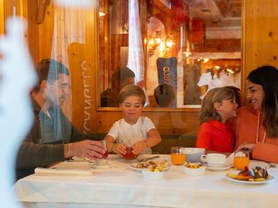 Famille assise à table avec de la nourriture dans un restaurant chaleureusement éclairé aux murs en bois.