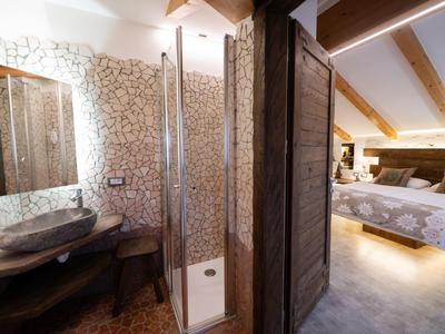 Salle de bain avec douche et chambre attenante dans une chambre d'hôtel avec poutres en bois.