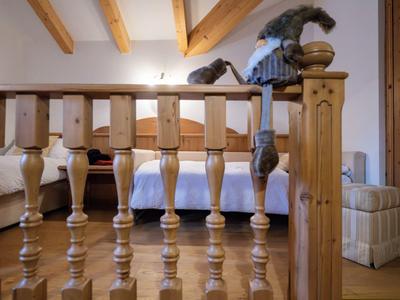 Lit avec balustrade en bois et poutres apparentes au plafond dans une pièce confortable