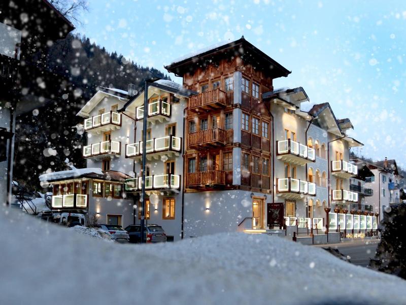 Hôtel éclairé dans un paysage montagneux enneigé avec chute de neige.