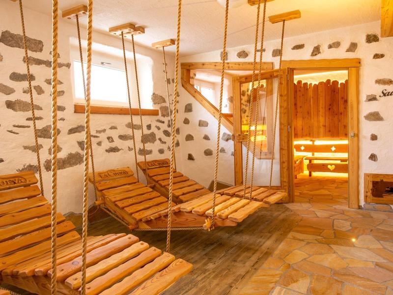 Espace de détente avec chaises suspendues en bois, éclairage chaud et sol en pierre dans un hôtel spa.
