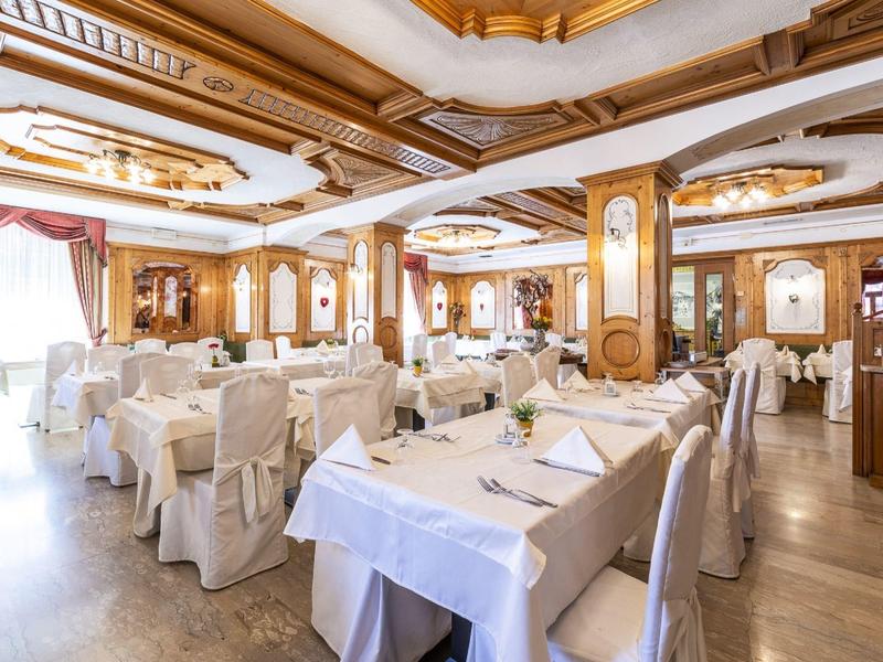 Salle à manger élégante et lumineuse avec tables dressées et housses de chaise blanches