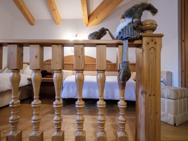 Lit avec balustrade en bois et poutres apparentes au plafond dans une pièce confortable