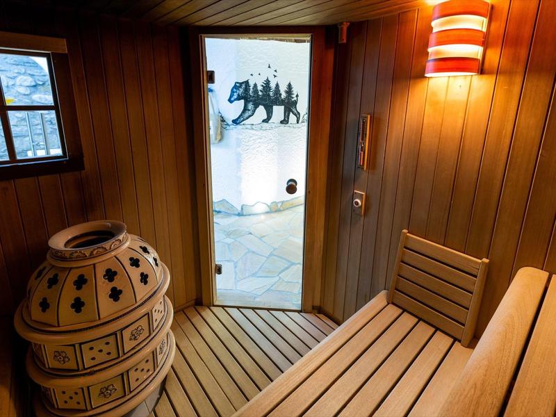 Salle de sauna confortable avec panneaux en bois, banc et poêle en céramique décoratif