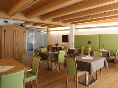 Sala colazioni moderna con soffitto con travi in legno e sedie verdi in un hotel.