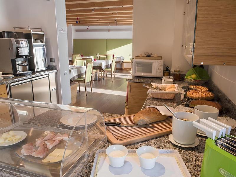 Area buffet con varie opzioni per la colazione in un hotel, area salotto visibile sullo sfondo.