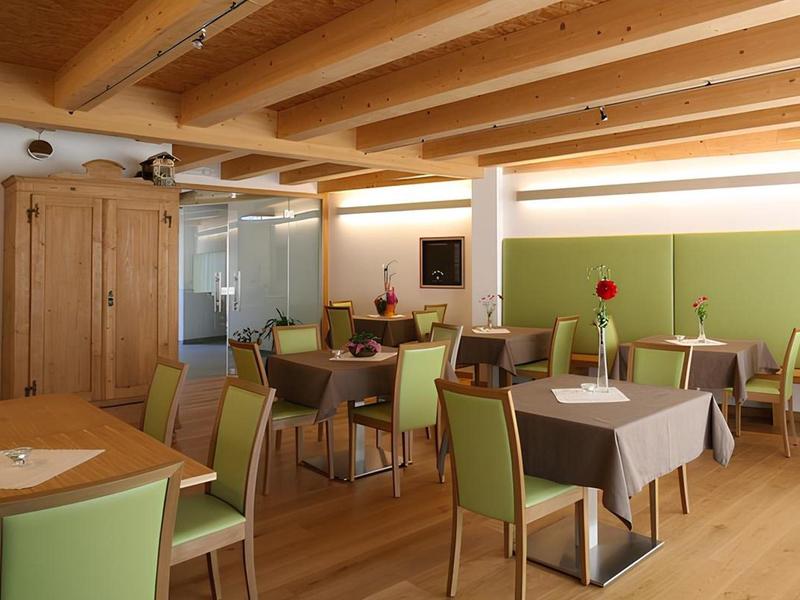 Sala colazioni moderna con soffitto con travi in legno e sedie verdi in un hotel.