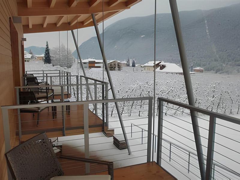 Balcone con sedie e ringhiera con vista su montagne e valle innevata