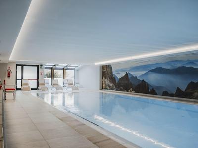Moderní vnitřní bazén s panoramatickým oknem a horami v pozadí