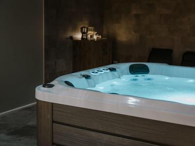 Osvětlená vířivka v temné místnosti s svíčkami v pozadí.