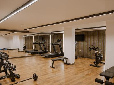 Gimnasio moderno con cintas de correr, mancuernas y bicicleta estática sobre suelo de madera.