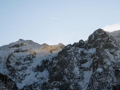 Sněhem pokryté horské vrcholy pod jasnou oblohou s slunečním světlem na vrcholcích.
