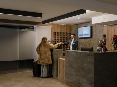 Host s zavazadly se u moderní hotelové recepce přihlašuje, personál podává klíčovou kartu.