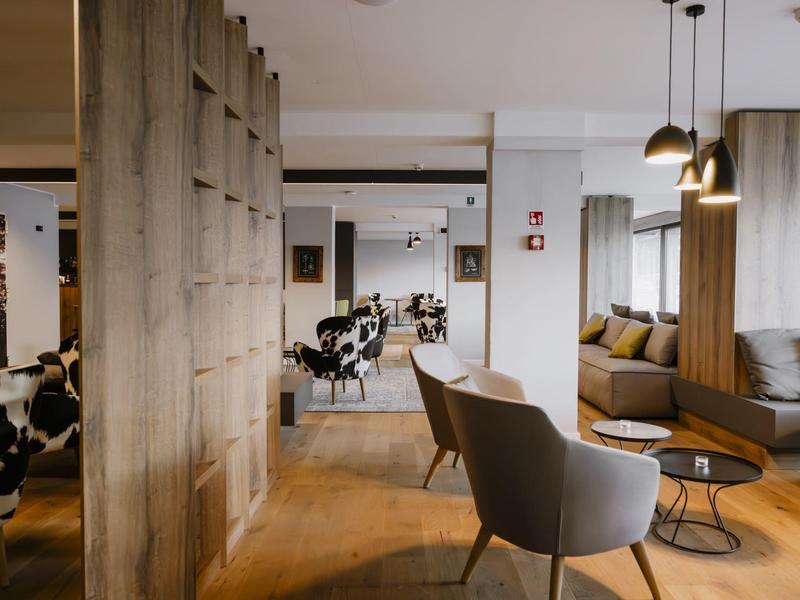 Moderní hotelová lounge s křesly, pohovkou a dřevěnými akcenty.