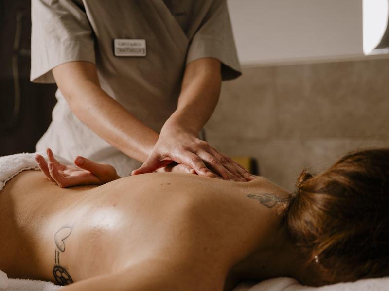 Osoba dostává relaxační masáž zad v klidném prostředí spa.