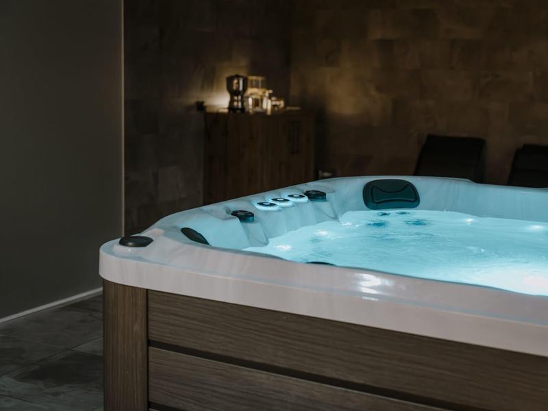 Osvětlená vířivka v temné místnosti s svíčkami v pozadí.