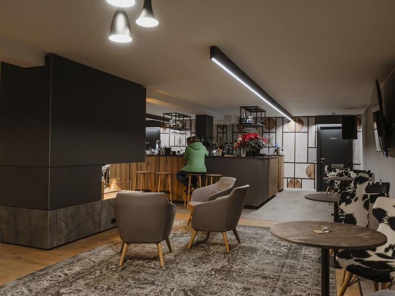 Moderně zařízená hotelová lounge s židlemi, lampami a rustikálním kobercem.