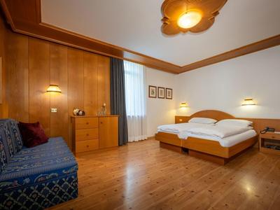 Chambre d'hôtel confortable avec lit double, canapé et meubles en bois.