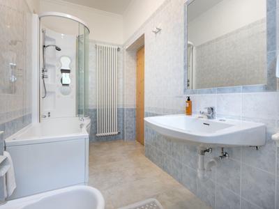 Salle de bain lumineuse avec baignoire, cabine de douche, lavabo et grand miroir.