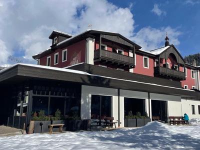 Bâtiment d'hôtel dans un paysage montagneux enneigé sous un ciel nuageux.